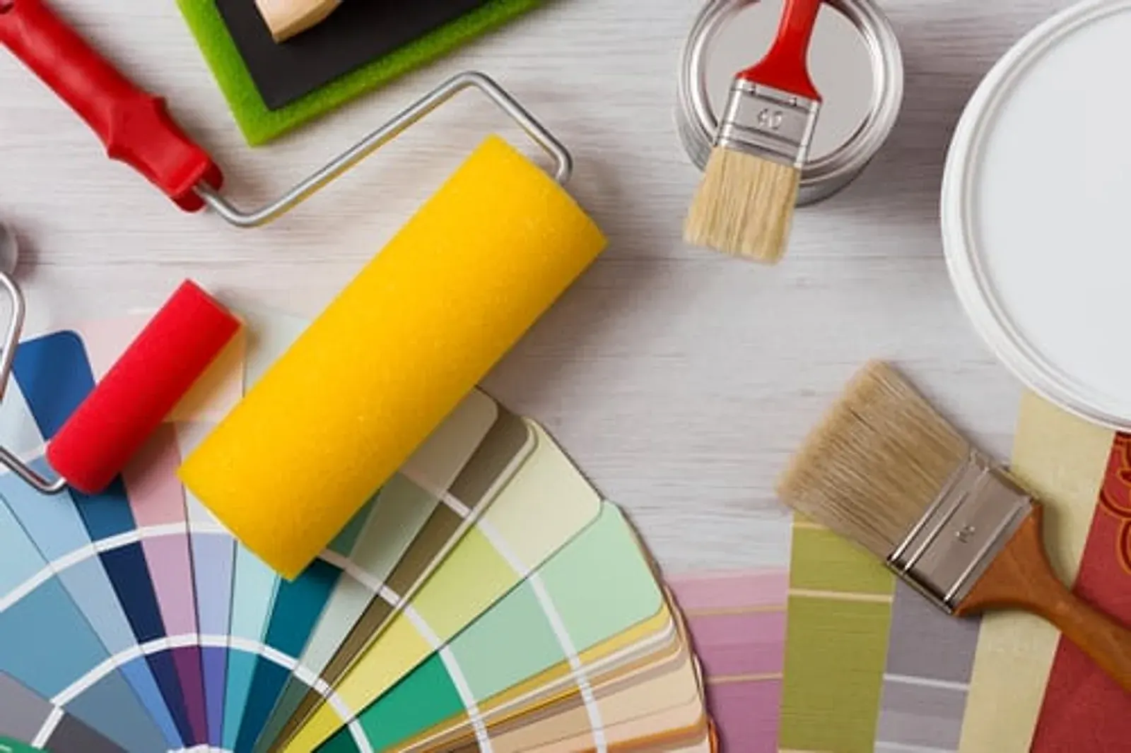 Paint roller, colour fan deck and brushes arranged on a workbench