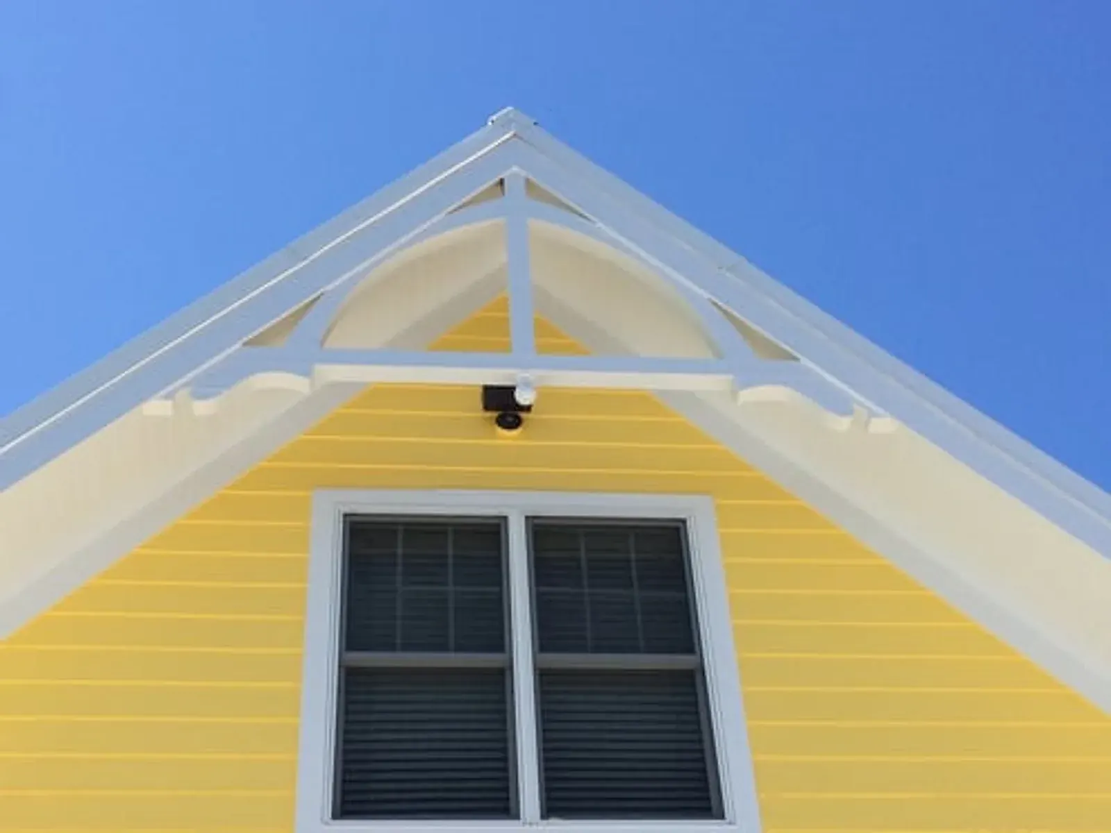 Freshly painted yellow gable and white trim against a clear blue sky