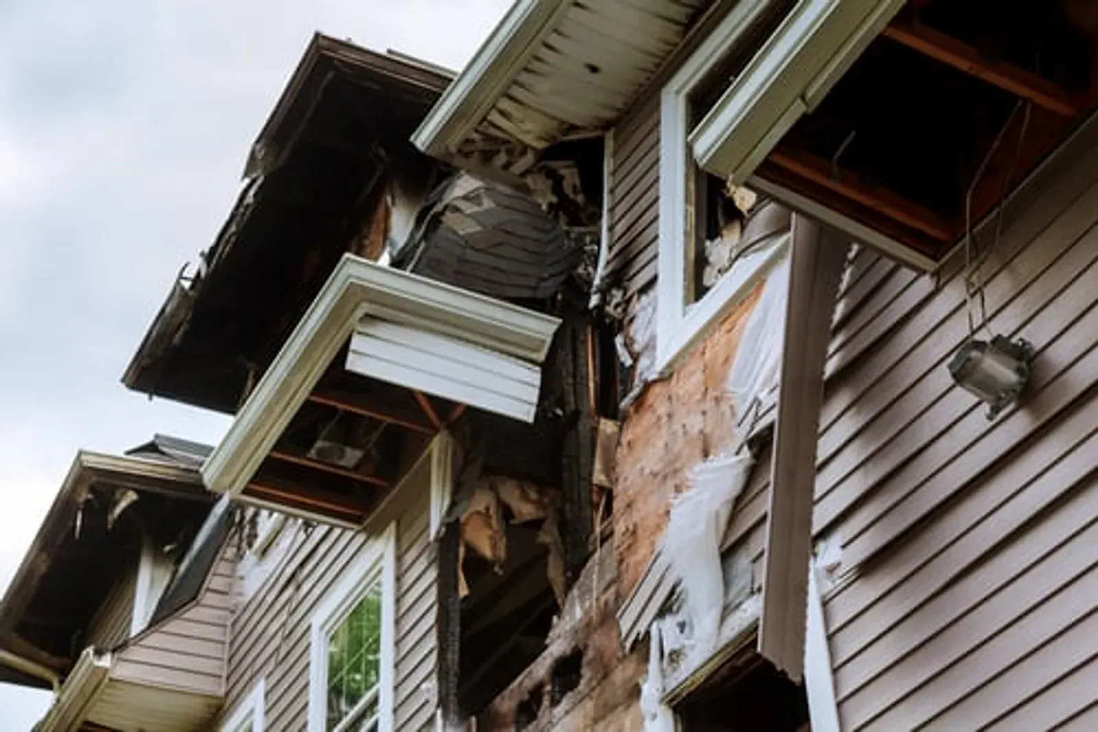 Damaged exterior siding boards pulling away from a house wall, awaiting repair